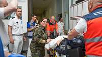 Großübung im Bundeswehrkrankenhaus Ulm Eine Person auf einer Trage liegend wird von Soldaten und Rettungskräfte durch einen Gang geschoben