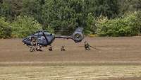 Soldaten sichern einen Hubschrauber, während andere Soldaten ihn betanken.