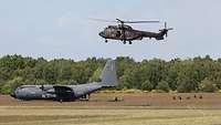 Ein Hubschrauber sichert ein gelandetes Flugzeug aus der Luft ab