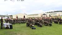 Sitzende Soldaten, stehender und predigender Militärpfarrer
