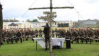 Ein Birkenkreuz, ein Altar, ein Pfarrer und teilnehmende Soldaten