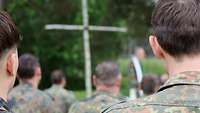 Blick auf ein Birkenkreuz über die Schulter eines Soldaten