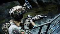 Ein Soldat mit Helm hält ein Gewehr in der Hand.