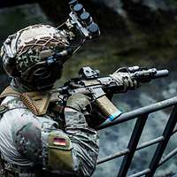 Ein Soldat mit Helm hält ein Gewehr in der Hand.