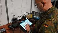 Ein Soldat schaut sich auf einem Tablet eine Karte an. 