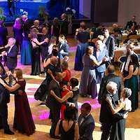 Bei einem Ball tanzen Menschen in Abendgarderobe auf der Tanzfläche.