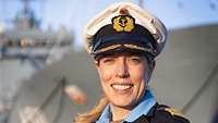 Eine Frau in Marineuniform vor einem Schiff.