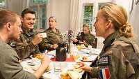Menschen sitzen zusammen beim Frühstück und unterhalten sich