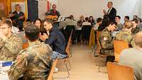 Ein Gitarrenspieler unterhält die Teilnehmer eines Frühstücks.