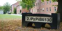 Blick auf einen Stein mit der Aufschrift 2./PzPiBtl130, im Hintergrund ein Gebäude