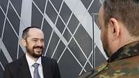 Ein Rabbiner mit Kippa spricht mit einem Soldaten in Flecktarn-Uniform