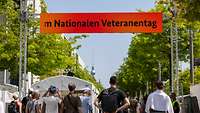 Eine Gitterkonstruktion mit einem LED Display, darunter stehen Menschen auf einer Straße