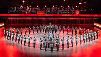 Soldaten musizieren in einer Halle mit rotem Licht.