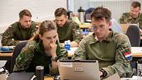 Soldatinnen und Soldaten arbeiten in Reihen hintereinander sitzend.