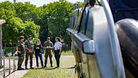 Soldaten und zivile Personen draußen im Gespräch.