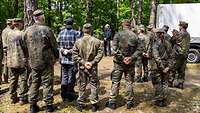 Soldaten stehen im Halbkreis und hören einem Redner zu