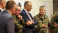 Friedrich Merz steht zwischen Soldaten und spricht mit ihnen