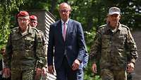 Friedrich Merz geht zwischen zwei Soldaten