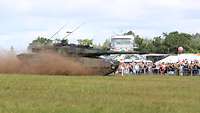 Tag der Bundeswehr 2025 in Greding Ein Panzer vom Typ Leopard fährt auf einer Wiese vor Publikum. Er wirbelt Staub auf.