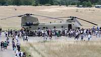 Menschen schauen sich den ausgestellten Transporthubschrauber CH-47 Chinook an