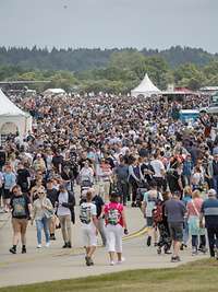 Viele Menschen bewegen sich auf einem Gelände mit ausgestellten Militärfahrzeugen und Infoständen