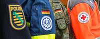 Nahaufnahme der Uniformen von Polizei, Technisches Hilfswerk, Bundeswehr und Deutsches Rotes Kreuz 