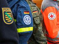 Nahaufnahme der Uniformen von Polizei, Technisches Hilfswerk, Bundeswehr und Deutsches Rotes Kreuz 