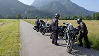 Motorräder stehen auf der Landstraße, im Hintergrund Berge der Voralpen