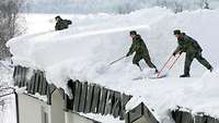 Soldaten räumen Schnee von einen Hausdach 