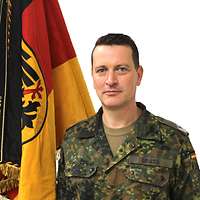 Portrait eines Soldaten neben einer Fahne. 