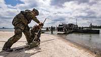 Zwei Soldaten machen eine Fähre mit einem Stahlseil an Land fest.