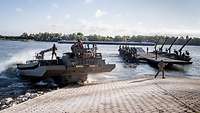 Eine Fähre auf dem Rhein, eine weitere Amphibie fährt in den Fluss.