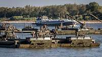 Mehrere Amphibienfahrzeuge schwimmen auf dem Rhein, im Hintergrund ein ziviles Schiff.
