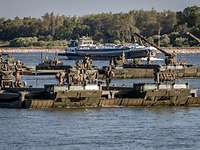 Mehrere Amphibienfahrzeuge schwimmen auf dem Rhein, im Hintergrund ein ziviles Schiff.