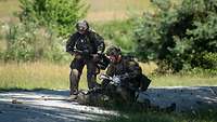 Ein Soldat liegt am Boden. Zwei Soldaten beugen sich zu ihm herunter. 