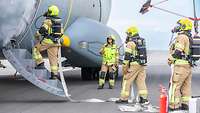 Bundeswehr-Feuerwehrleute stehen bei einer Übung neben einem A400M, aus dem Qualm herausdringt 