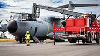 Der Transportkorb eines Feuerwehrfahrzeugs ist bei einer Übung an das Cockpit eines A400M herangefahren.