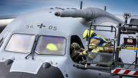 Eine Person im Tragekorb des Feuerwehrfahrzeuges rettet eine große menschliche Puppe aus dem Cockpit.