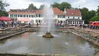 Ein Brunnen, dahinter ein Schloss
