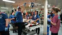 Sanitätspersonal steht um einen Behandlungstisch mit Übungspatienten während der Übung Role2Sea