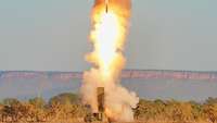 Ein Fahrzeug mit einer Abschussrampe schießt eine Rakete ab. Eine große Feuerwolke entsteht.