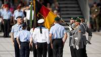 Soldaten stehen neben der Deutschlandfahne in Grundstellung