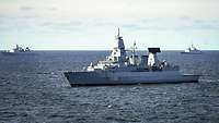 Drei Kriegsschiffe verschiedener Nationen fahren auf dem Meer