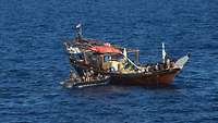 Soldaten in einem Schlauchboot bringen ein Holzboot auf während der Anti-Piraterie-Mission Atalanta