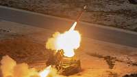 Ein großer Feuerball entsteht hinter einer aus einem Patriot-Startgerät austretende Rakete.