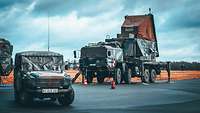 Ein PATRIOT-Radar steht auf einer Freifläche. Davor parkt ein militärisches Geländefahrzeug.