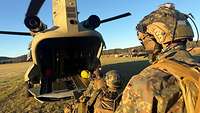 Auf dem Weg zum Einsatzgebiet Blick von hinten auf das geöffnete Heck eines Hubschraubers: Soldaten steigen hintereinander ein.