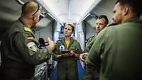 Seefernaufklärer P-8A Poseidon – Ausbildung in den USA Vier Soldaten stehen im Gang eines Flugzeugs. Ein Soldat spricht und die anderen hören ihm zu.