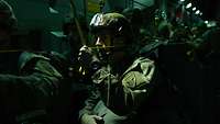 Soldaten mit Fallschirmen stehen bei Nacht sprungbereit an der Flugzeugtür.