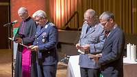 Zwei Soldaten und zwei Pfarrer stehen nebeneinander und lesen vor dem Altar die Fürbitten.